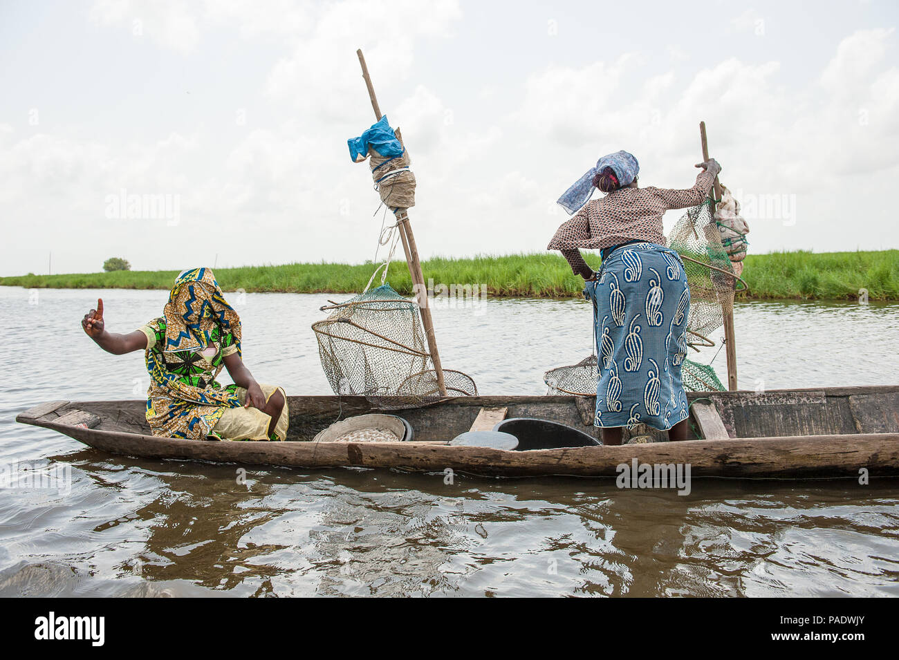 - PORTO NOVO, BENIN - Mar 9, 2012: Unbekannter Beninischen zwei Frauen Segel ein Fischerboot. Bevölkerung von Benin Leiden der Armut aufgrund der schwierigen wirtschaftlichen Stockfoto