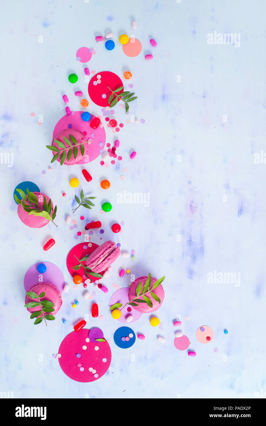 Macaroon Cookies auf einen farbigen Hintergrund mit Konfetti. Lebendige Partei Konzept mit kopieren. Rosa und Lila palette Flach. Stockfoto