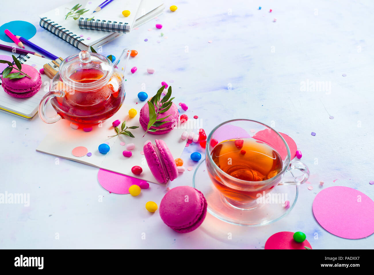 Teekanne aus Glas Header mit Bonbons und Konfetti auf hellem Hintergrund mit kopieren. Rosa und Lila Palette noch leben. Lebendige Tea Party Getränke Konzept Stockfoto