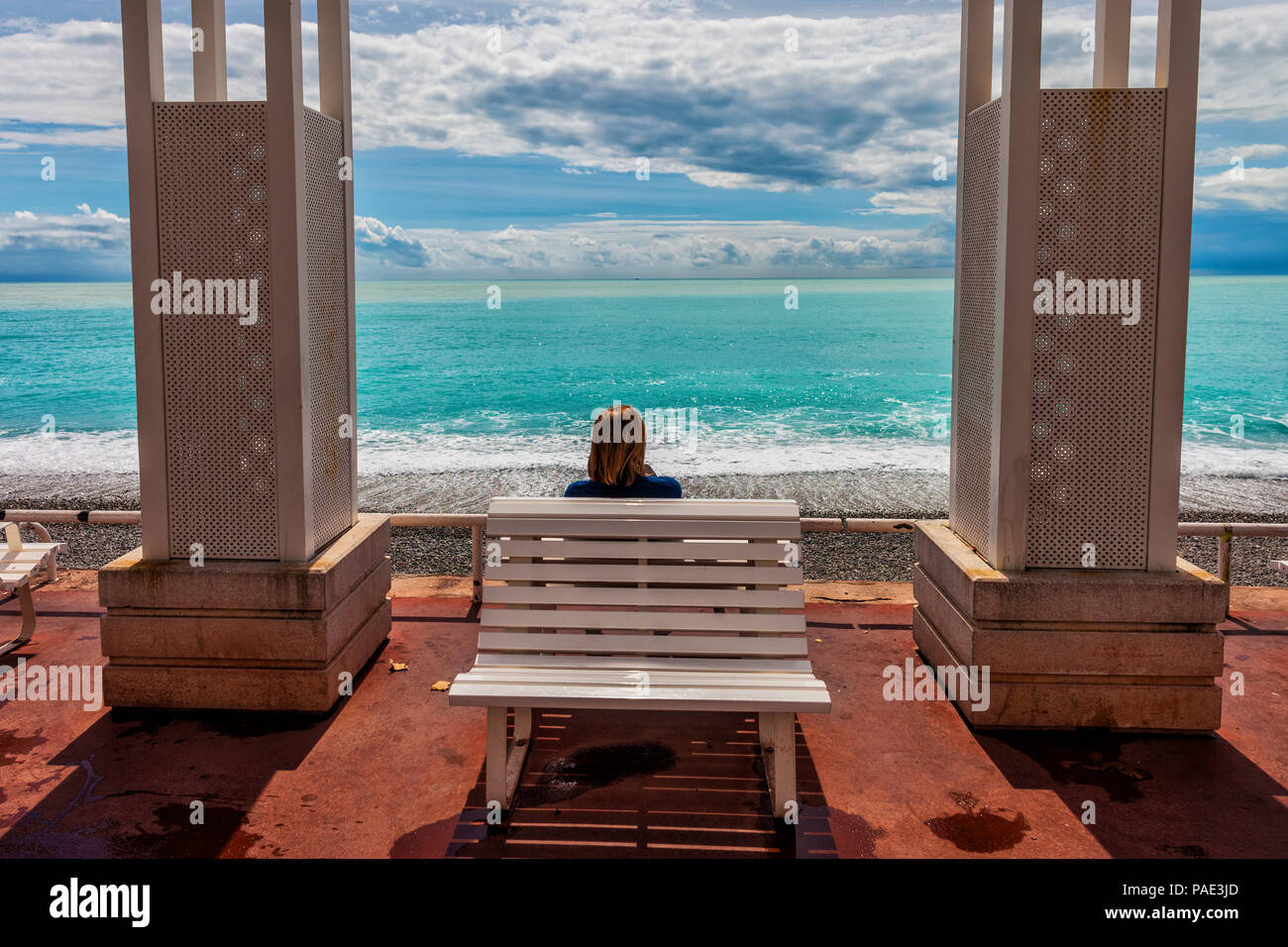 Schöne Stadt Frankreichs, die einzelne Frau mit Blick auf das türkisfarbene Wasser des Mittelmeers, Pergola Sitzbank an der Promenade des Anglais und die Französische Riviera Stockfoto
