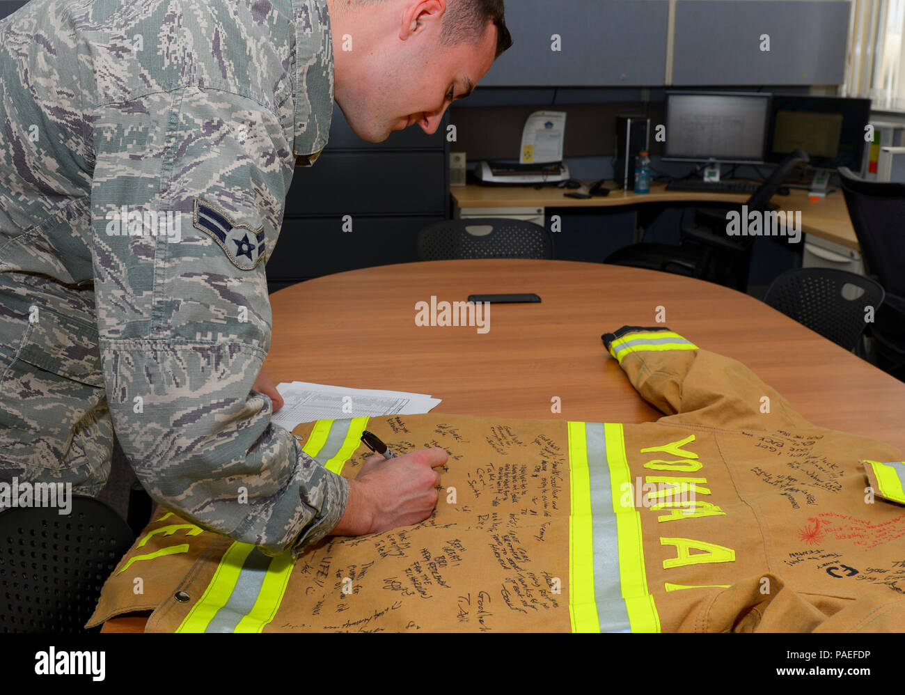 Airman 1st Class, 374th Civil Engineer Squadron Fire and Emergency Services Fire Fighter, unterzeichnet am 28. März 2016 eine Brandschutzjacke auf der Yokota Air Base, Japan, in Anerkennung eines pensionierten Mitglieds. Die Zeremonie würdigt die Beiträge des Dienstes, fördert die Kameradschaft der Einheit und pflegt Traditionen im Einsatz der Feuerwehr und der Rettungsdienste. Stockfoto