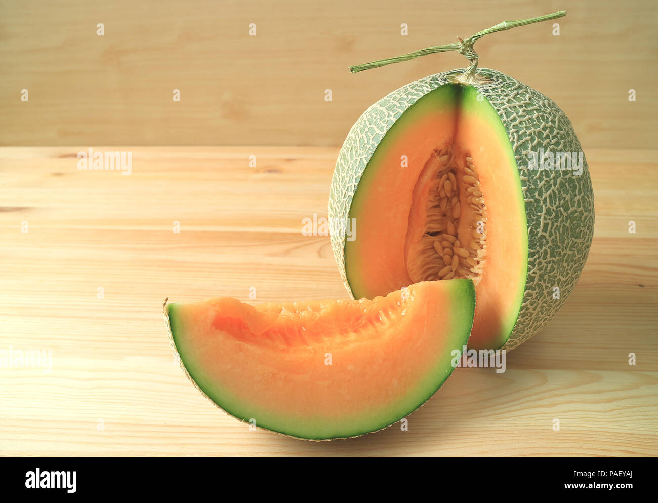 Helles orange Farbe saftige reife Zuckermelone geschnitten aus ganzen Früchten auf Holztisch, isoliert Stockfoto