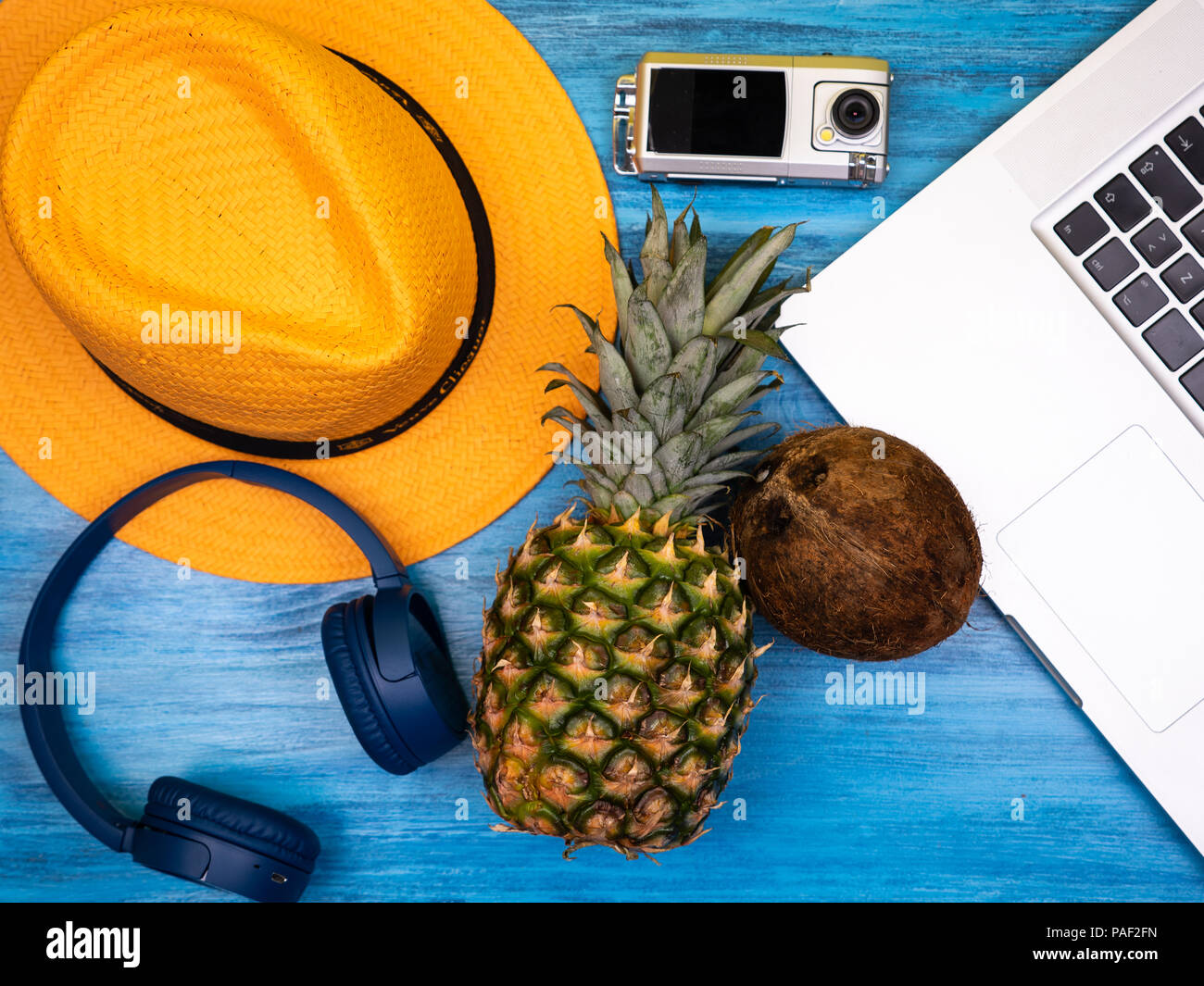 Hut, Kopfhörer, Action Kamera, Laptop, Ananas und Kokosnuss Stockfoto