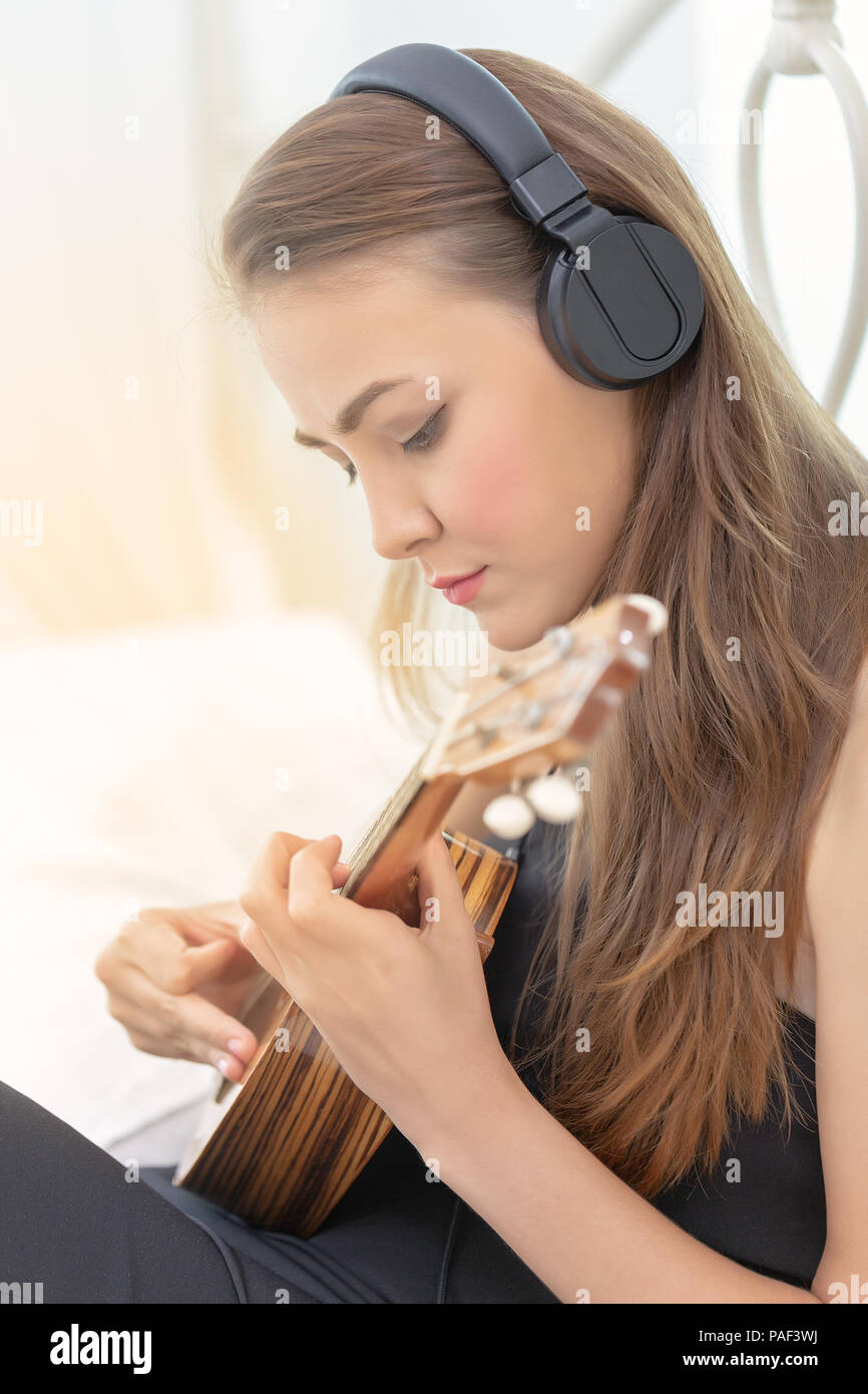 Junge glücklich Mädchen spielen oder üben Sie Musik auf akustische Gitarre oder Ukulele. Stockfoto