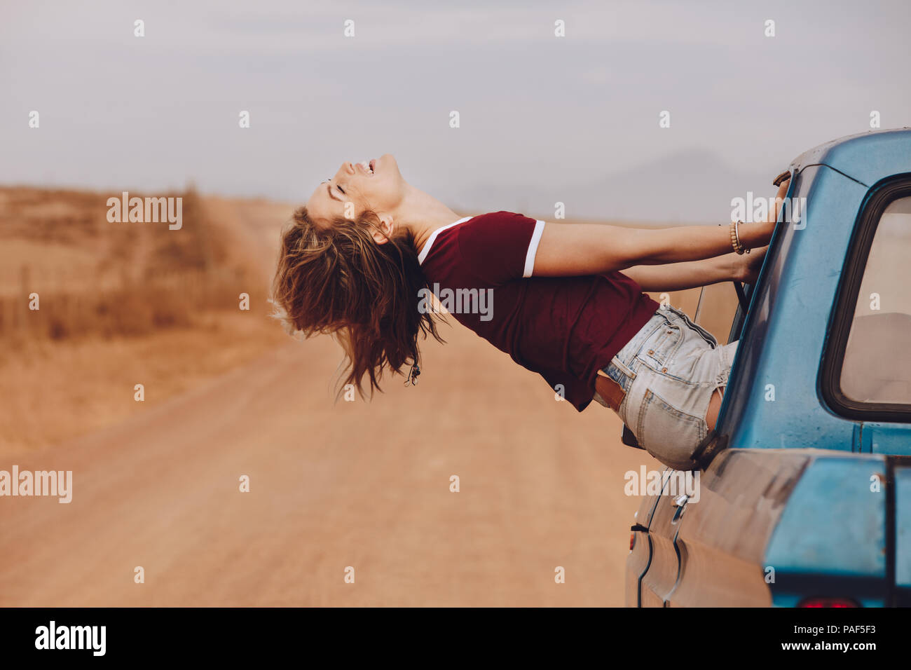 Schöne junge Frau sitzt am Fenster und sah lächelnd. Weibliche genießen die Fahrt mit dem Auto über Land road trip. Stockfoto