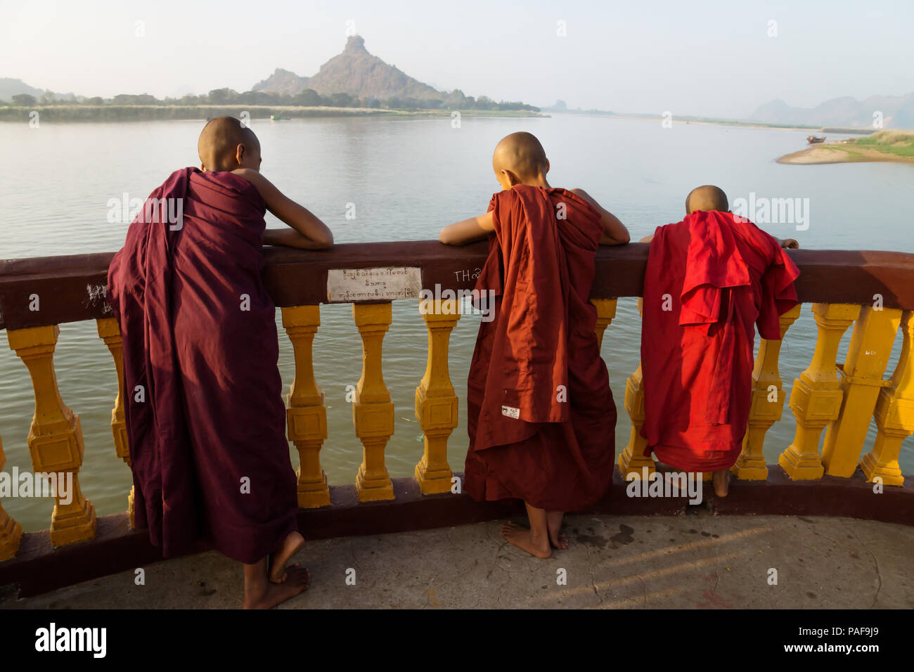 Drei Mönche an der Pagode entlang des Flusses mit Berg in Hpa-an, Myanmar Stockfoto