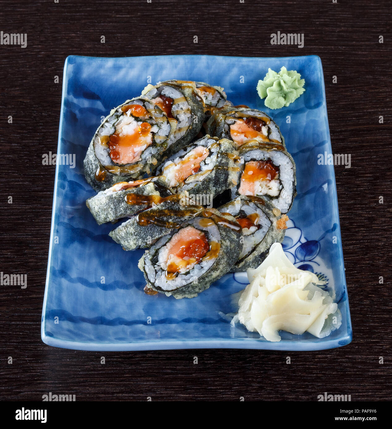 Sushi rollen auf einem Teller mit Lachs und Gurke auf Holztisch. Stockfoto