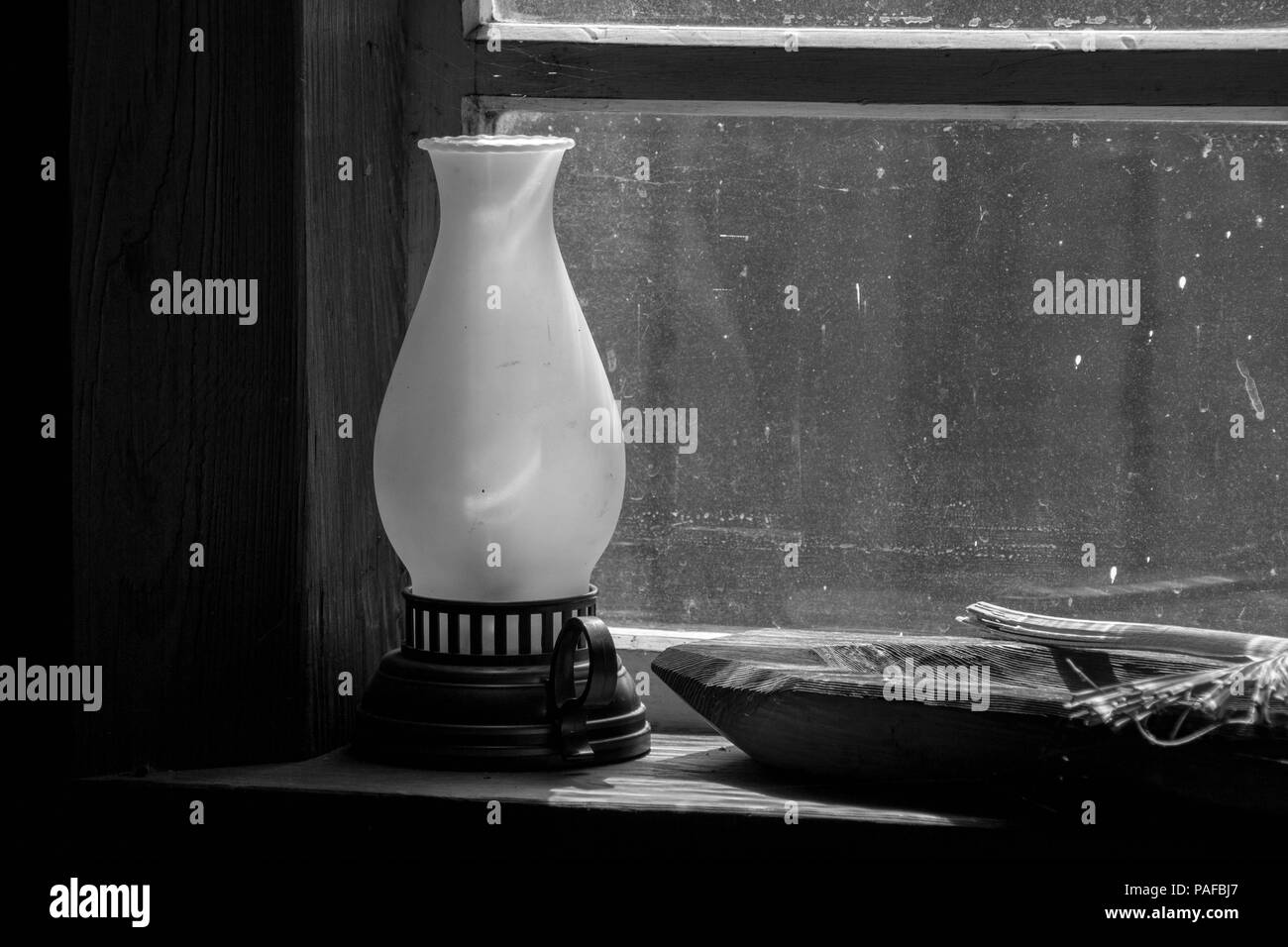 Magere bedeutet: Eine einfache schwarz-weiß Foto von einer Laterne, vintage Fenster und ein Graben gestaltete hölzerne Schüssel. Starke Kontraste und Schatten. Stockfoto
