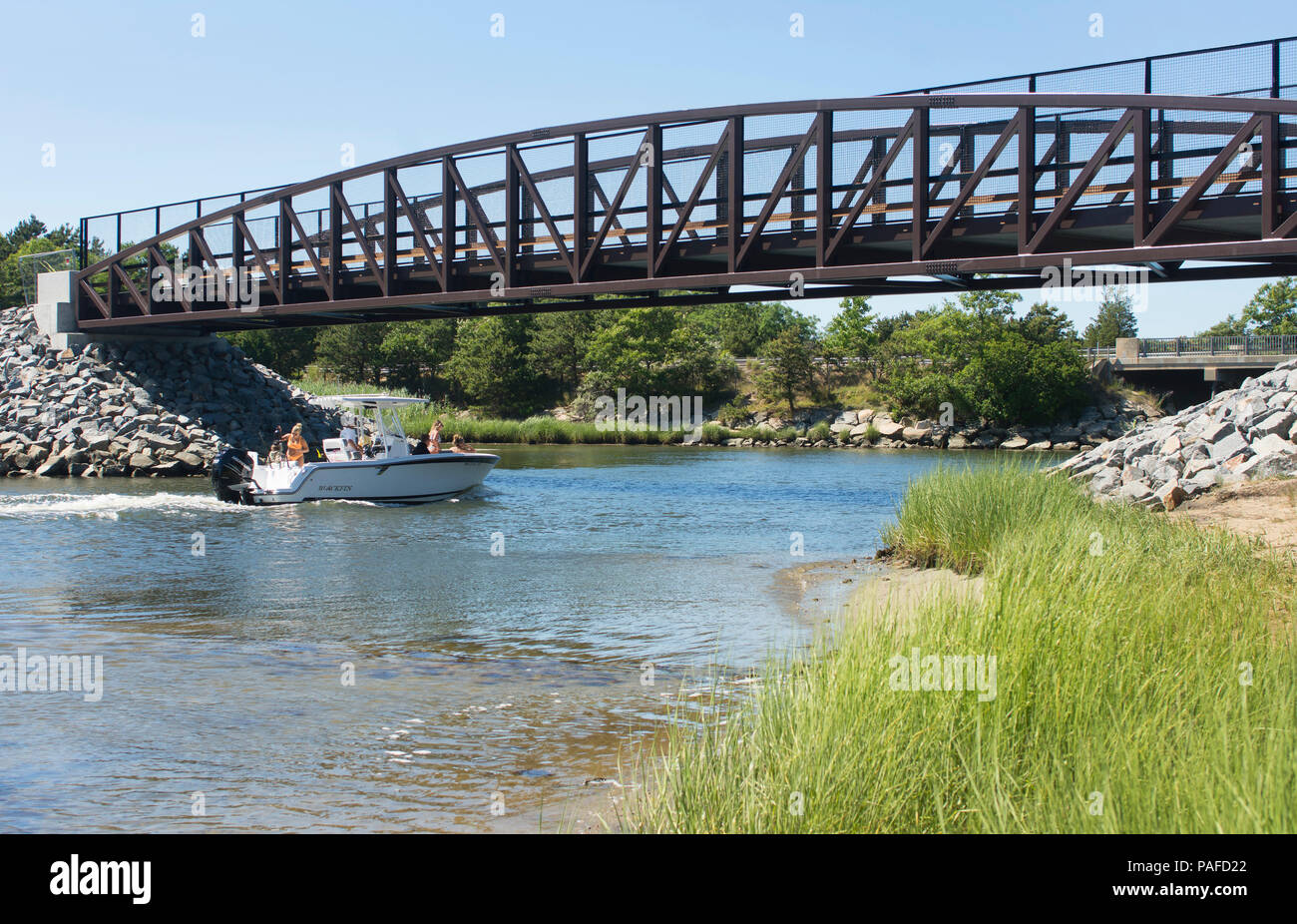 Ein Motorboot geht unter einen Radweg Brücke überspannt den Bass River in Dennis, Massachusetts, USA Stockfoto