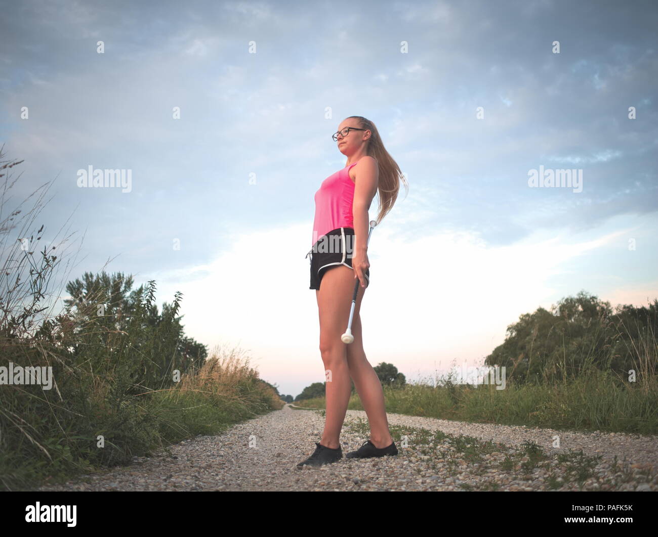 Bebrillter blonder Teen Majorette Mädchen Twirling Baton im Freien Training Kleidung Stockfoto