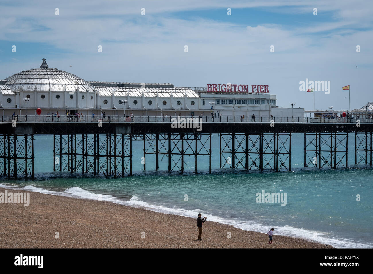 Brighton Pier an einem sonnigen Tag mit Wellen am Strand unten Stockfoto