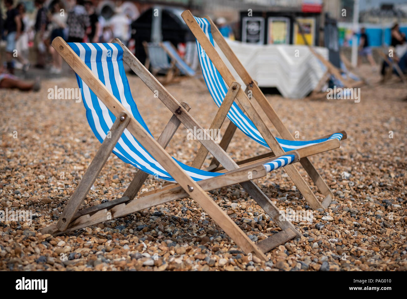 Zwei Liegestühlen sitzen auf einem Kieselstrand mit Blick aufs Meer in Brighton, Großbritannien Stockfoto