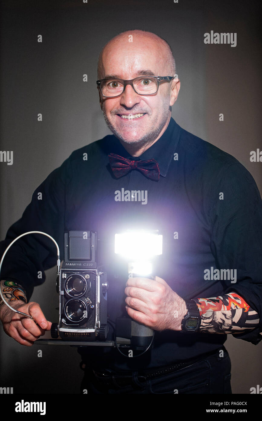 Selbstportrait des Fotografen holding Film Kamera Mamiya C220 mit Blitz Metz 45 CT-5. 45, 50, 55, 60 Jahre alt. Stockfoto