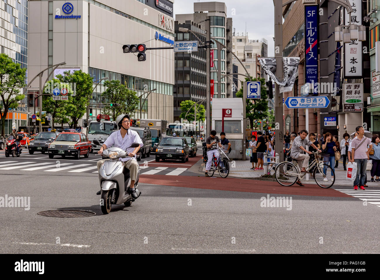 Mann auf dem Moped Warten auf grünes Licht an der Kreuzung von Tokyo Straße, während Fußgänger an der Kreuzung warten. Stockfoto