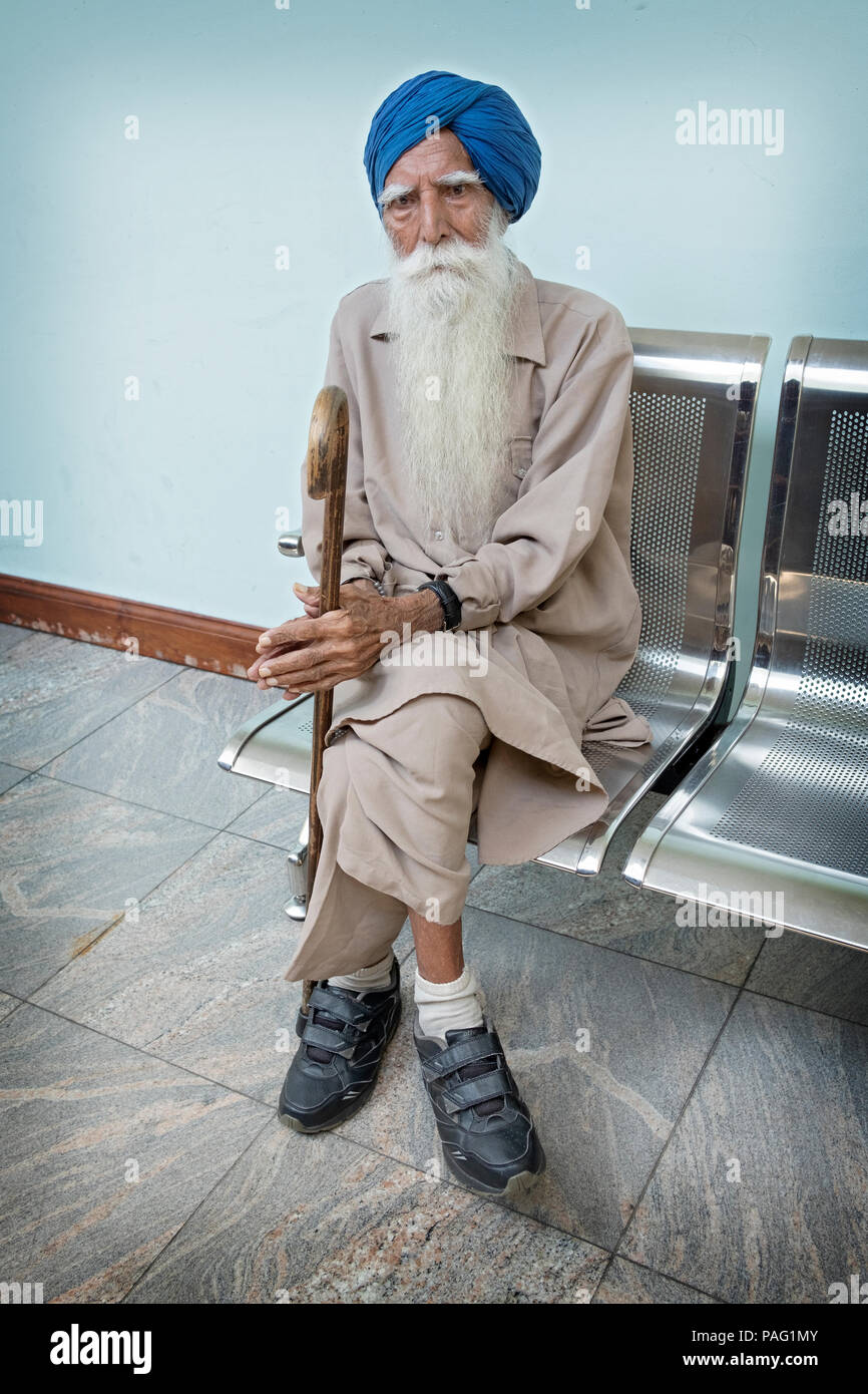 Portrait eines älteren Sikh Mann sitzt und seinen Stock Holding. In Richmond Hill, Queens, New York. Stockfoto