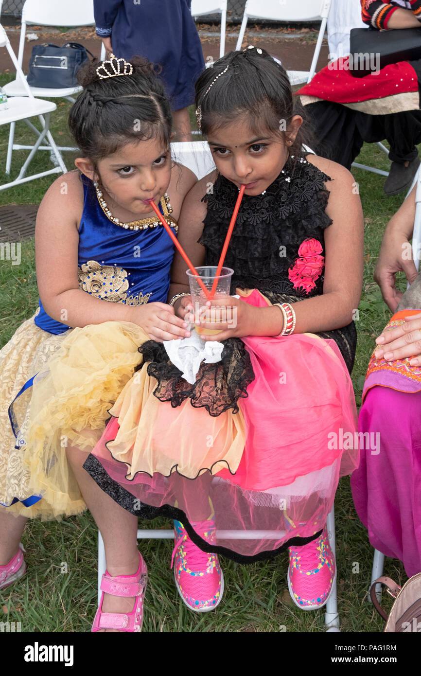 Cute Sikh Schwestern teilen ein kaltes Getränk an einem Sommertag in der Sikh Gurmat Spiele an Smokey Park in South Richmond Hill, Queens, New York. Stockfoto
