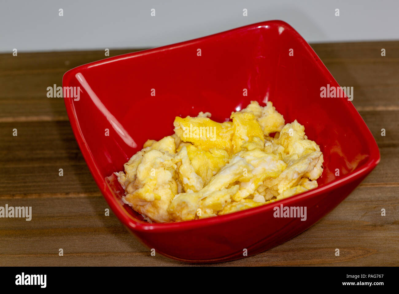 Eine rote Schale mit Rührei zum Frühstück auf den Tisch warten, gegessen zu werden. Stockfoto