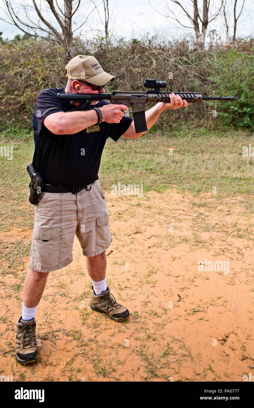 Ein Mann steht in einem bewaldeten Gebiet in den Geltungsbereich einer AR-15 Gewehr beim anvisieren Stockfoto