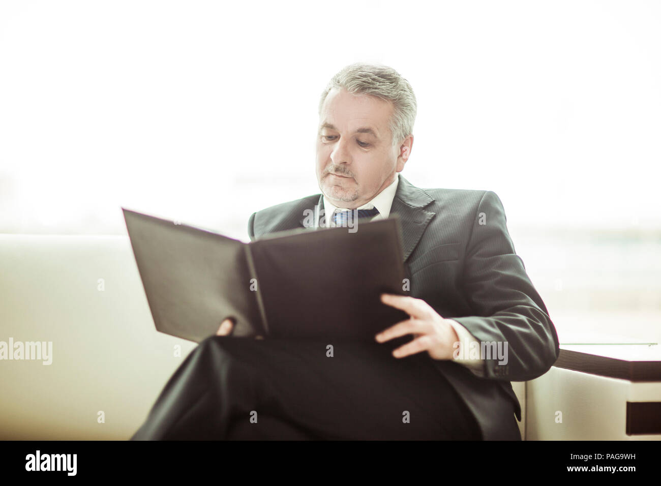 Erfolgreicher Geschäftsmann Studien Working Papers auf dem Sofa sitzen im eigenen Büro Stockfoto