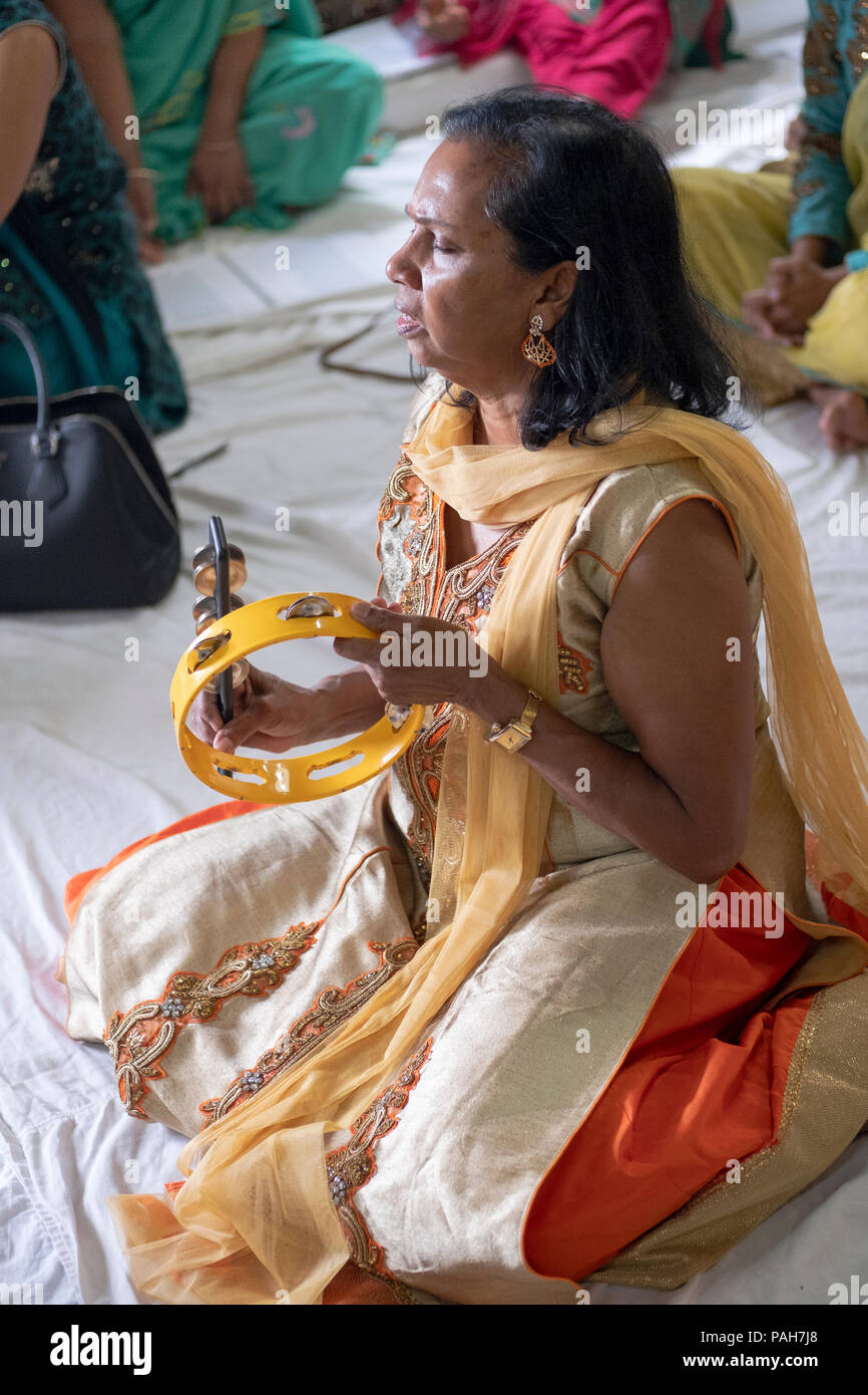 Ein Hindu Frau sitzen und spielen Schlaginstrumente der Mailand Mandir Hindu Tempel in South Ozone Park, Queens, New York. Stockfoto