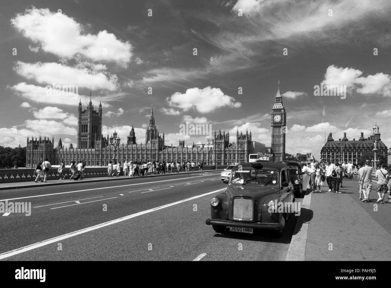 Ein schwarz-weiß Bild eines Londoner Taxi auf die Westminster Bridge als Touristen angehalten Ihren Weg an das Parlament und den Big Ben Stockfoto