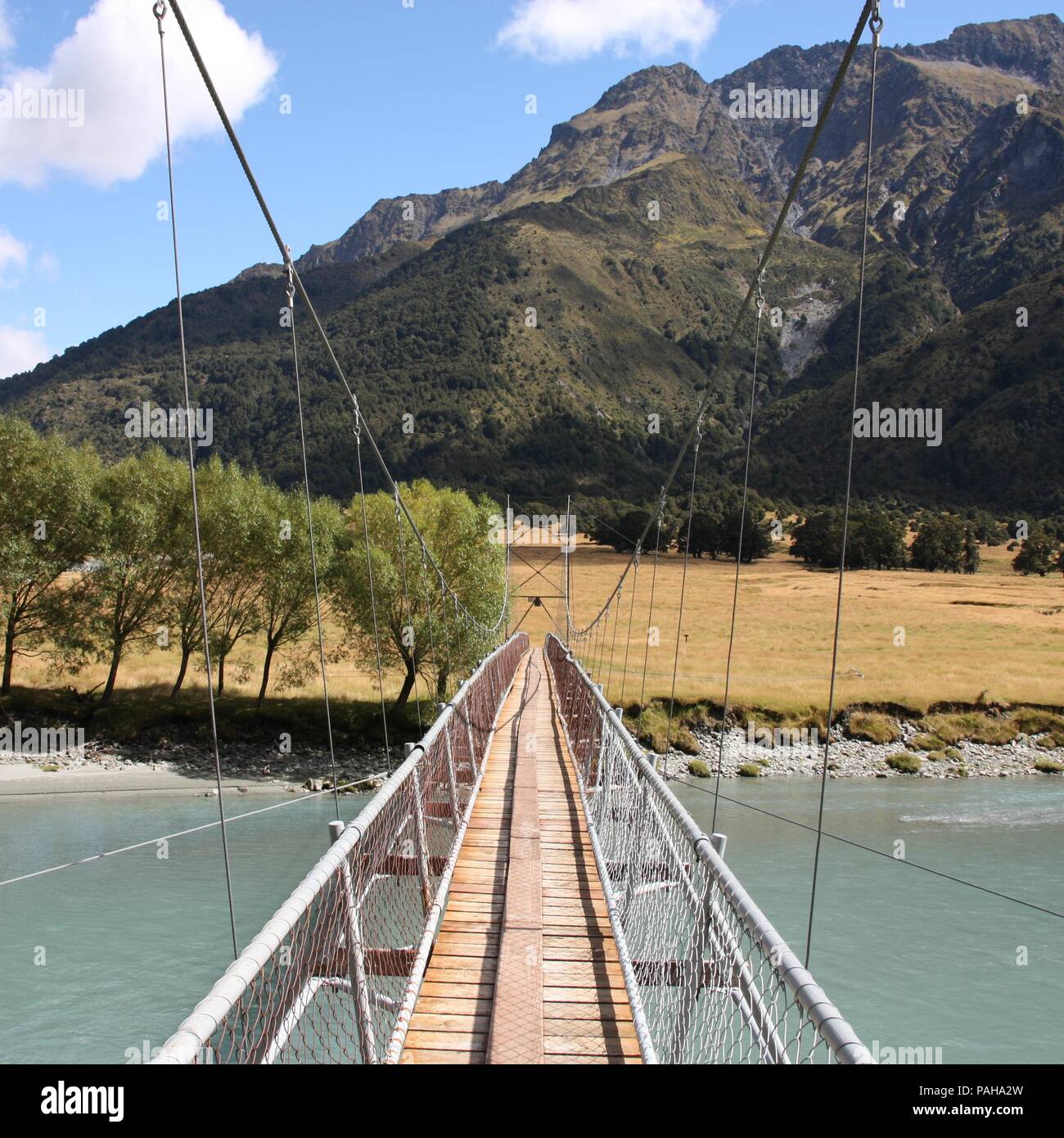 Neuseeland. Hängende kabel Brücke - River Crossing auf einem Wanderweg im Mount Aspiring National Park. Quadratische Komposition. Stockfoto