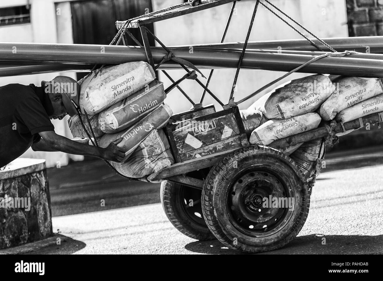 ANTANANARIVO, Madagaskar - 27. JUNI 2011: Unbekannter Madagaskar Mann schiebt eine Beförderung Bau. Menschen in Madagaskar Leiden der Armut durch. Stockfoto