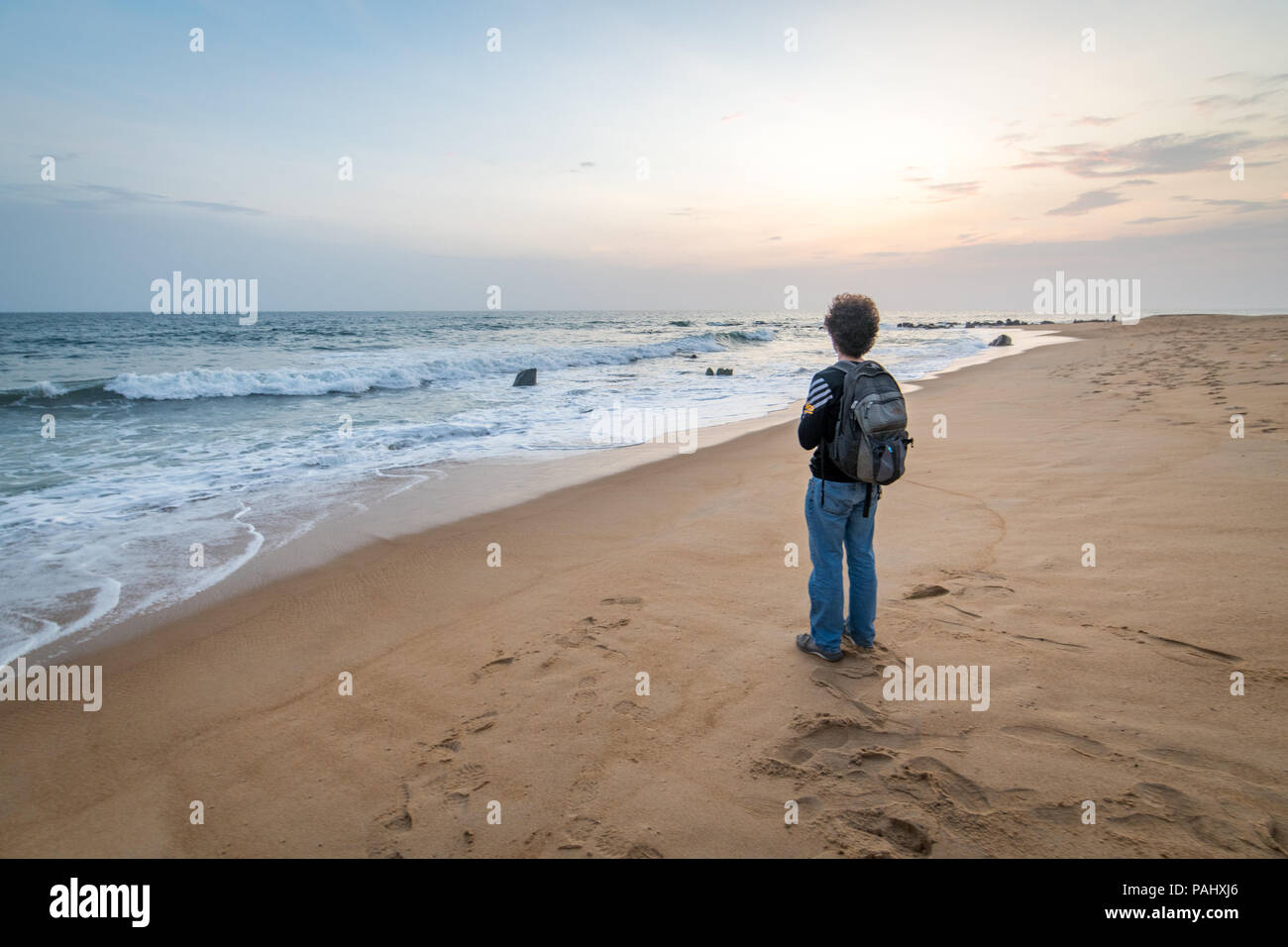 Ein Reisender steht auf dem Strand in die Wellen Monrovia, Liberia suchen Stockfoto