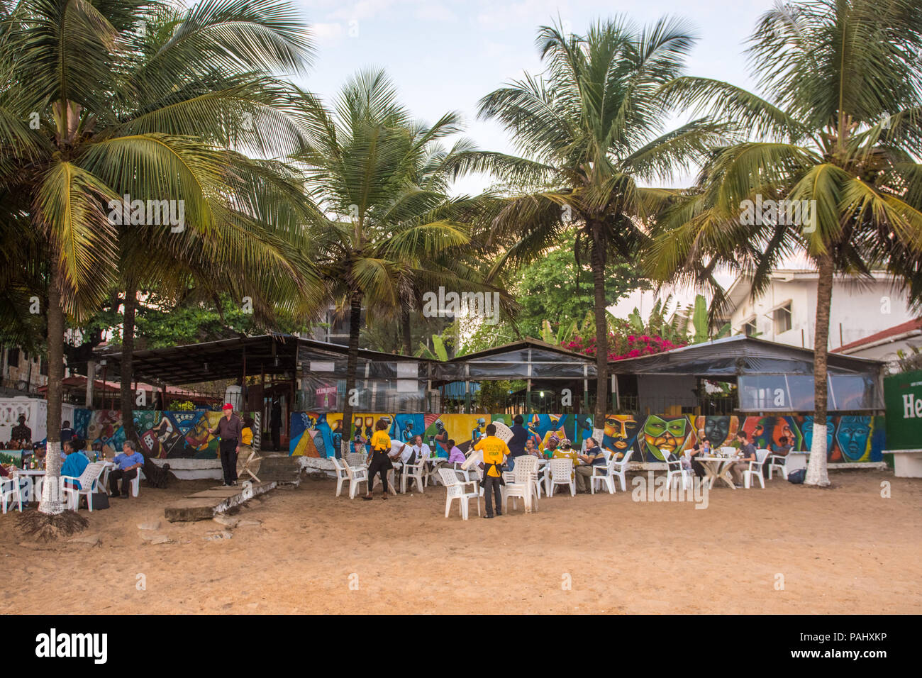 Gruppen von Menschen an den Tischen entlang dem Strand in einem Restaurant sitzt. Monrovia, Liberia Stockfoto