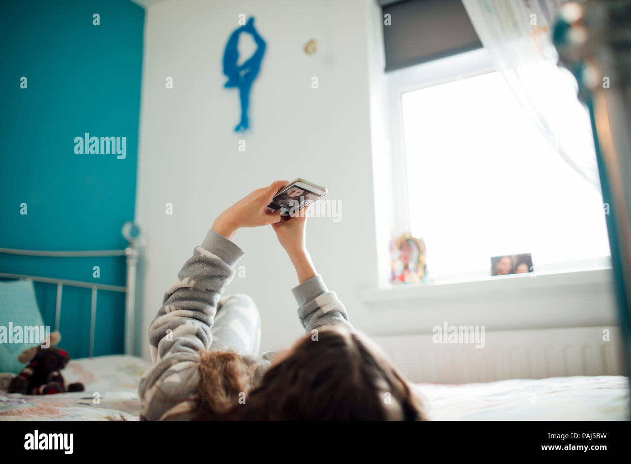 Kleines Mädchen liegt auf ihrem Bett, wobei selfies auf Ihrem Smartphone. Stockfoto