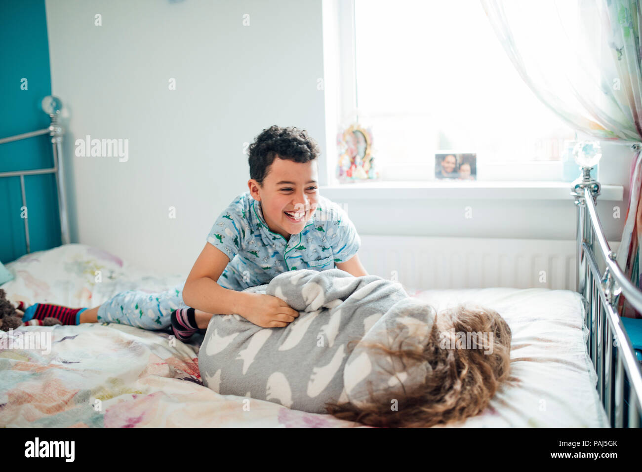 Little Boy und seine ältere Schwester sind playfighting auf einem Bett zu Hause. Stockfoto