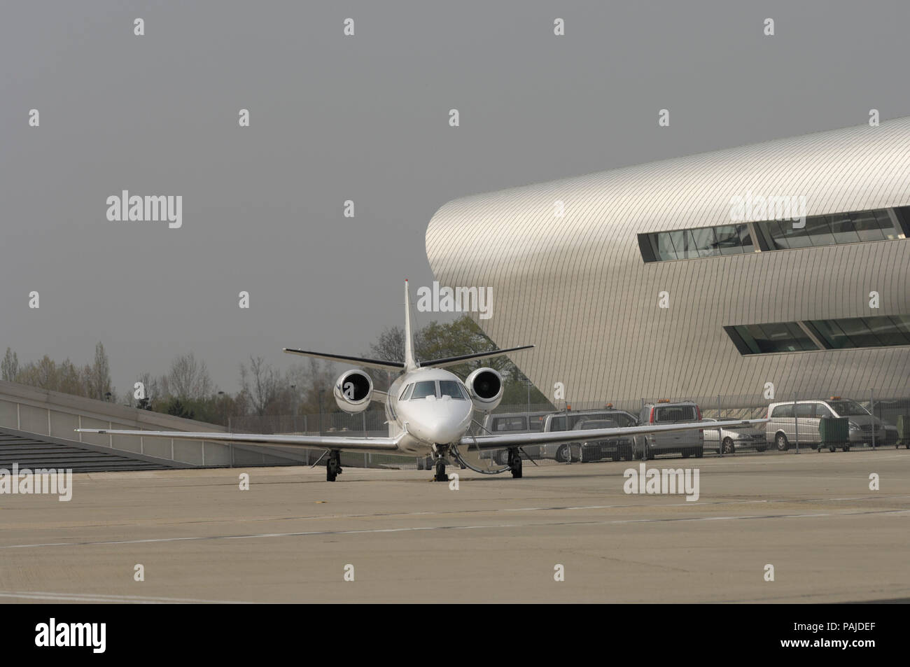 Eine Cessna Cessna Citation 560 XL Citation Excel auf dem Vorfeld mit dem TAG Aviation Terminal hinter geparkt Stockfoto