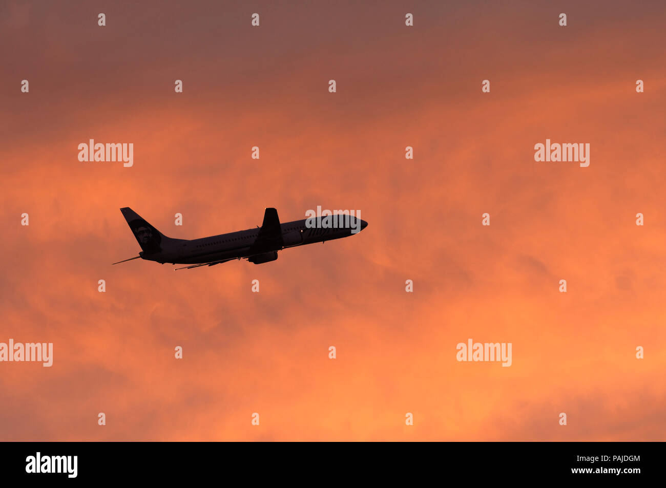 Eine Alaska Airlines Boeing 737-900Fliegen auf dem Weg in einen rosa Himmel in der Abenddämmerung. Dieses Flugzeug wurde die erste Boeing 737-900je gebaut wurde Stockfoto