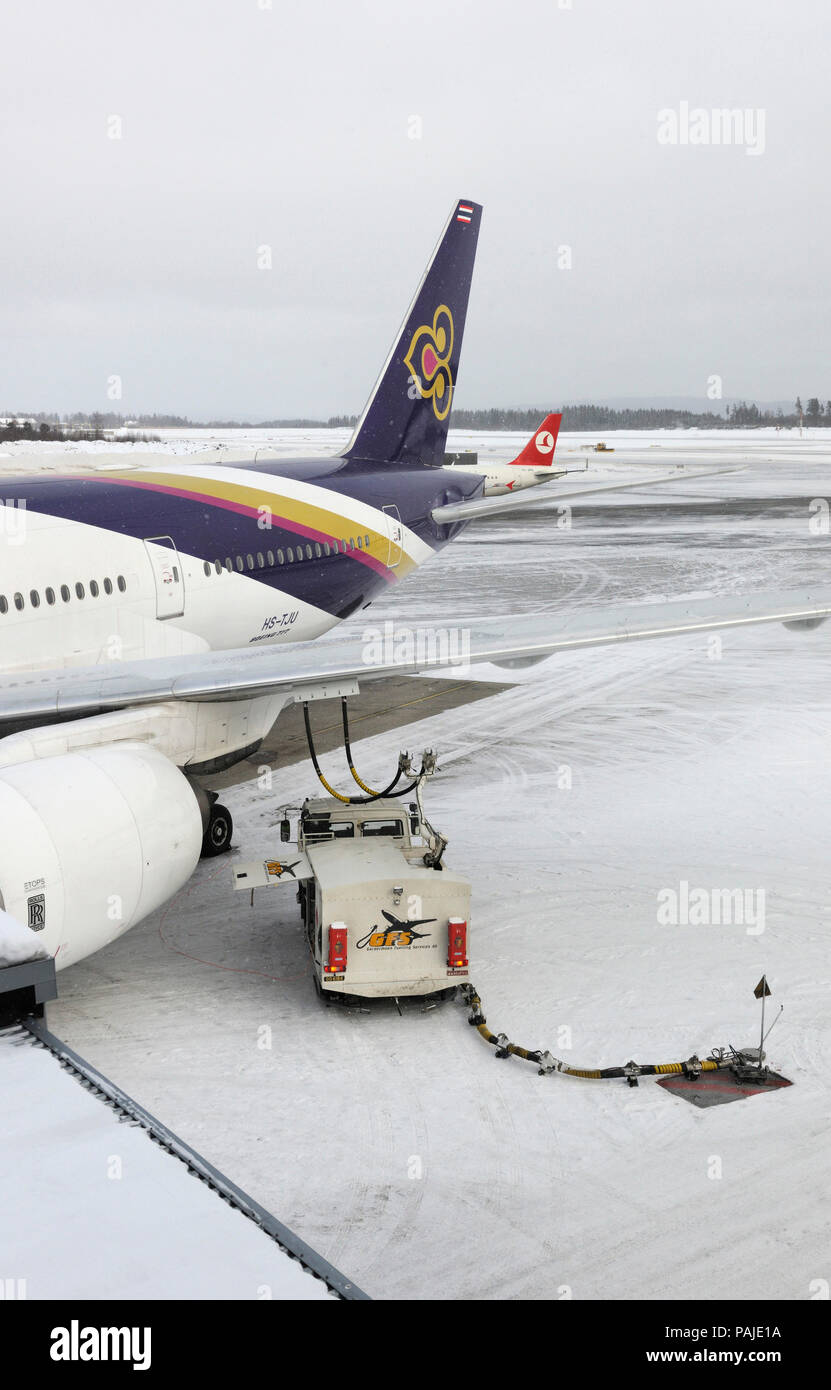 Tanken Lkw mit Schläuchen angebracht unter dem Flügel von Thai Airways International Boeing 777-200ER und heckflosse von Turkish Airlines 737 hinter geparkt Stockfoto