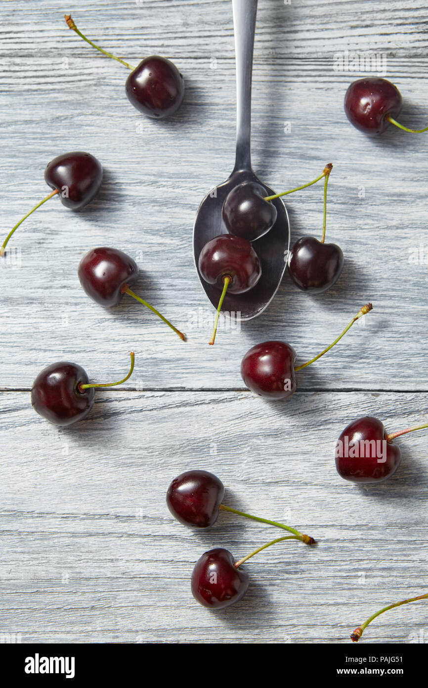 Süße Beeren Hintergrund von rot reifen Kirschen wth Löffel auf grau Holz- Hintergrund. Flach. Stockfoto