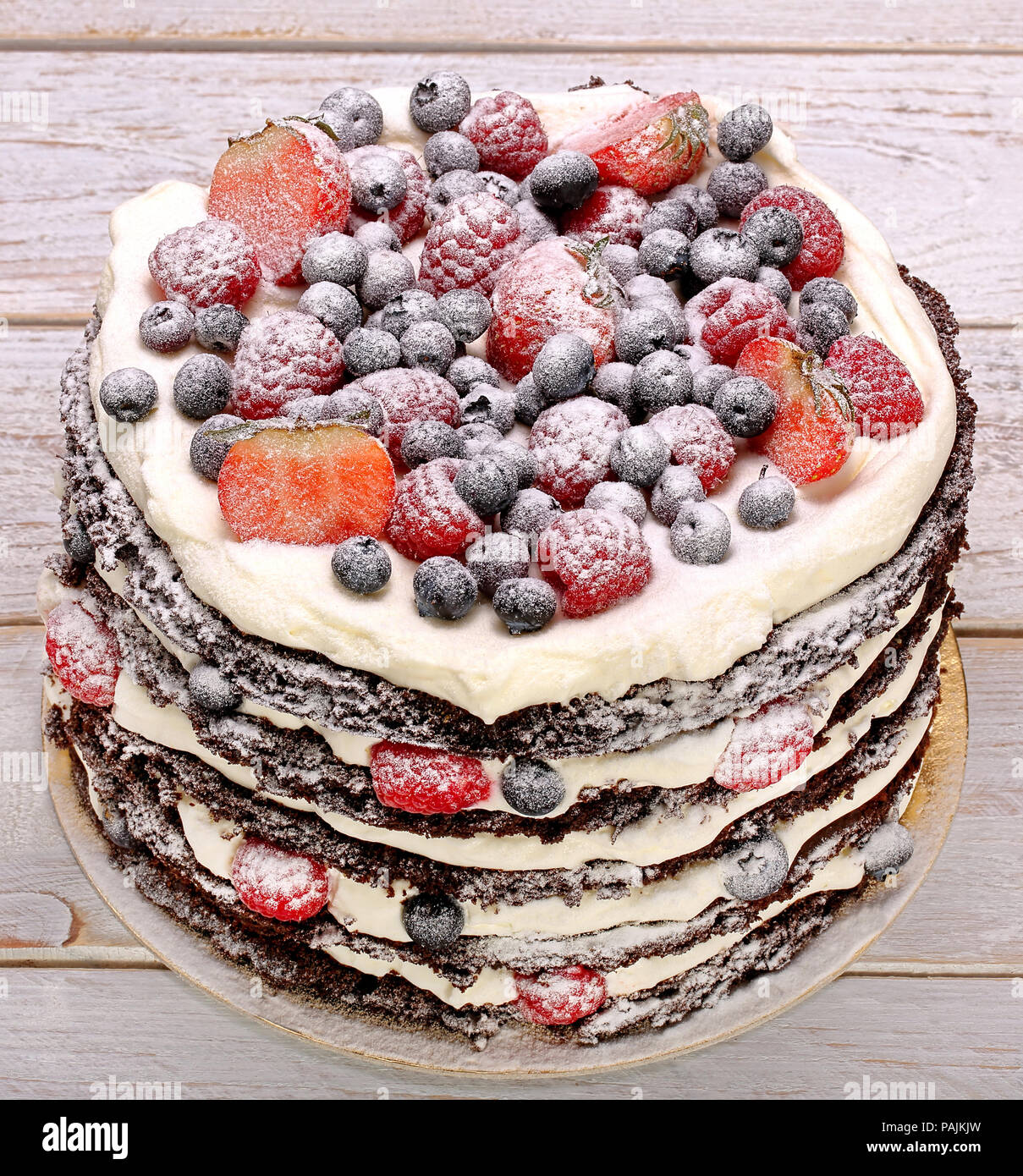 Schokoladenkuchen mit Sahne und frischem Obst auf hölzernen Hintergrund Stockfoto