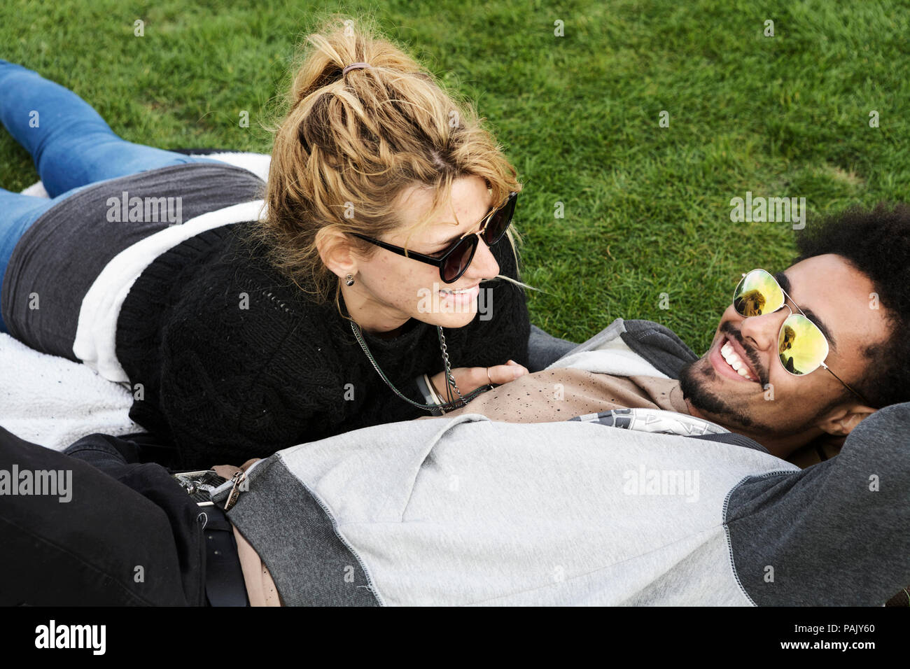 Millennials, liegend, in einer Sonnenbrille, lächelnd. Junge gemischte Beziehung Lebensstil Liebe. Alltag. Freizeit Stockfoto