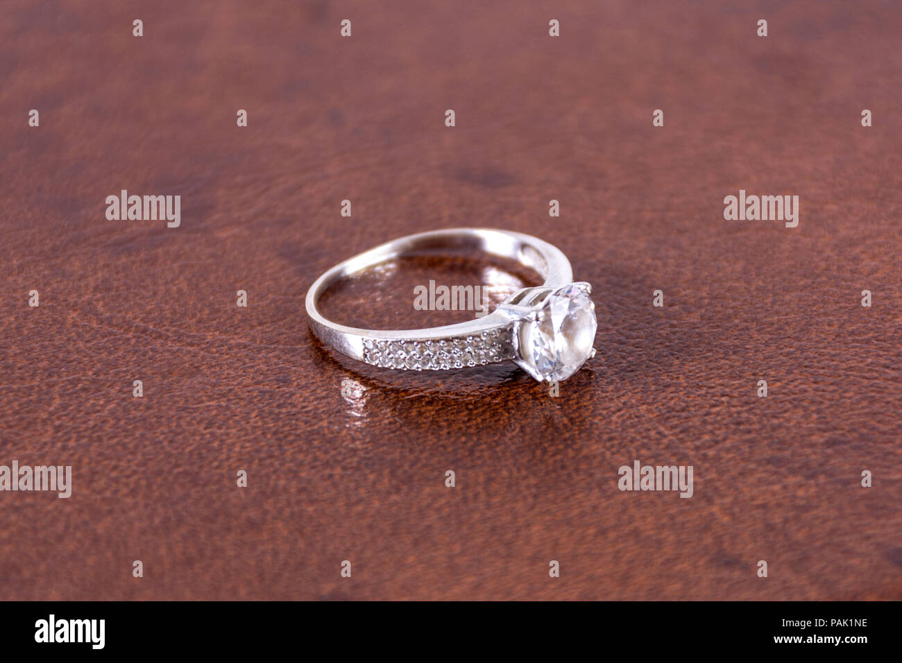 Diamond silber Verlobung Hochzeit Ring auf Leder braun verschwommen und weichem Hintergrund im Studio. Liebe und heiratete Konzept. Close Up, selektiver Fokus Stockfoto