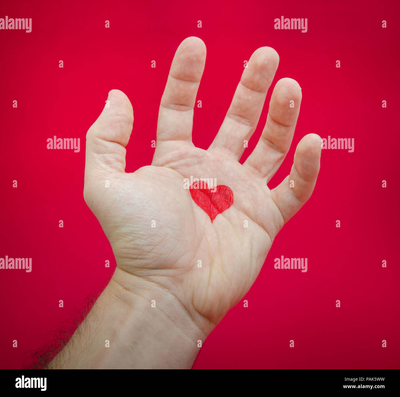 Liebe tut weh und schafft den Schmerz nach der Beziehung von einem Herz auf eine Hand vor Frust und Schmerz auf einer roten alarmiert seriuos Hinterg vorgeschlagen wird Stockfoto