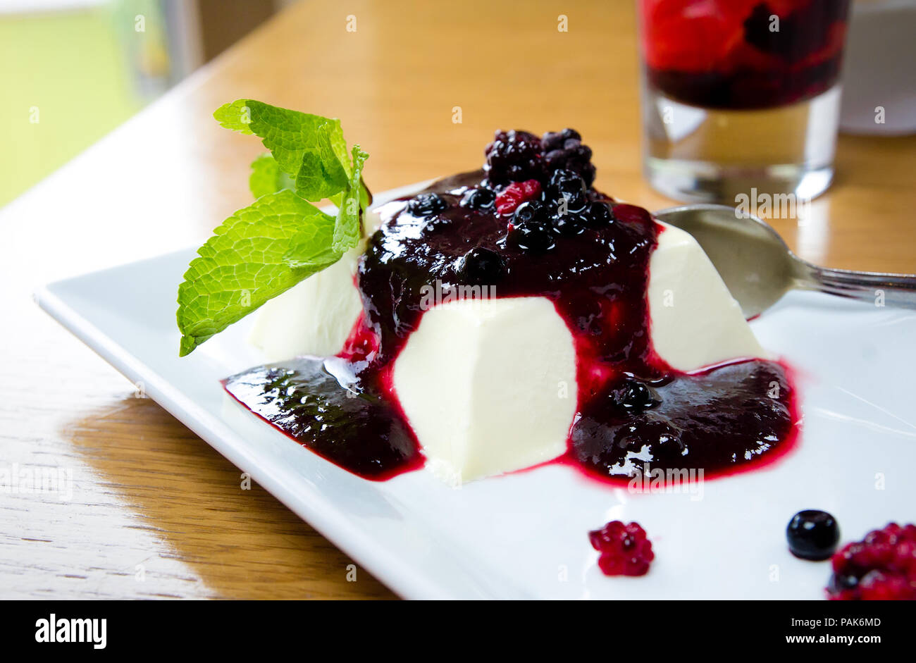 Panna cotta mit rabspebrry Marmelade und Minze auf einem weißen minimalistisch rechteckigen Platte an einem sonnigen Tag Stockfoto