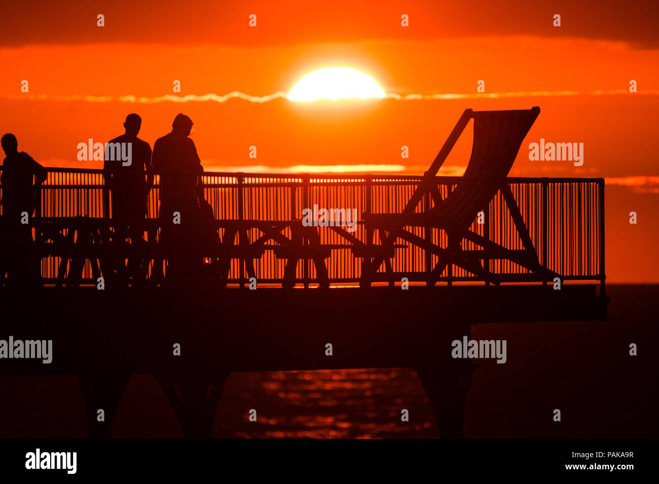 Aberystwyth Wales UK, Montag, 23. Juli 2018 UK Wetter: Menschen, die von den herrlichen Sonnenuntergang über Aberystwyth Pier Silhouette am Ende der heißesten Tag des Sommers so weit, mit Temperaturen Hoechststand von 33,3°C im Santon Downham, Suffolk. Großbritannien große Hitzewelle fort, ohne Atempause von der sehr trockenen Wetter, und das Met Office hat ein 'Wärme Health Watch Alert für viel der Osten und Südosten Englands Photo Credit: Keith Morris/Alamy Live Neuigkeiten Stockfoto