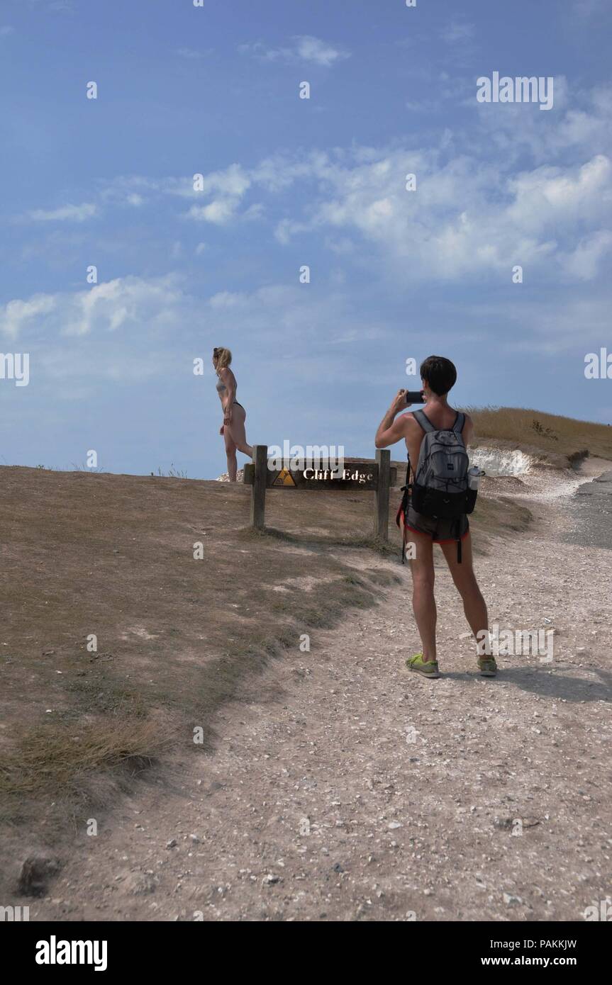 Beachy Head, East Sussex, UK. 24. Juli, 2018. Trotzt eine schriftliche Verwarnung, ein junges Weibchen touristische Risiken Tod für ein Foto bei Beachy Head, East Sussex. Die Kreidefelsen sind notorius für Selbstmorde und Rock fällt vom erodierenden Klippen. Credit: Dario Earl/Alamy leben Nachrichten Stockfoto