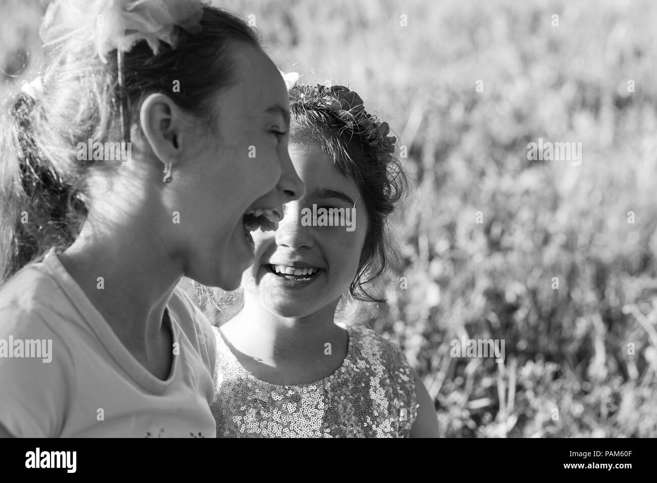 Zwei glückliche kleine Mädchen lachend und Umarmen im Sommer Park. Happy chidhood Konzept. Schwarz-weiß Foto. Für text Stockfoto