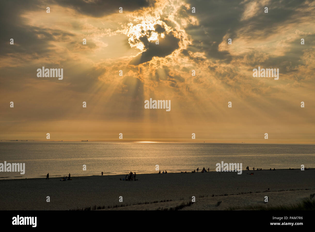 Menschen am Strand bei Sonnenuntergang in den heißesten Sommer in Holland überhaupt, der Strand ist in der Nähe von europoort mit den Schiffen am Horizont Stockfoto