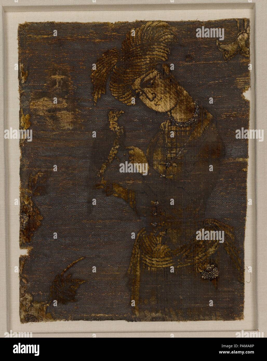 Ein junger Mann an einen Falken. Abmessungen: Textil: L. 11 1/2 in. (29,2 cm) W. 8 1/2 in. (21,6 cm): L 16 cm. (41 cm) W. 13 1/4 in. (33,7 cm) D.1 1/2 in. (3,8 cm). Datum: Anfang des 17. Jahrhunderts. Die ursprüngliche Breite dieses Textil würde mindestens vier Zahlen Rücken-an-Rücken spiegelbildlich enthalten haben. Ein junger Mann, der in einem voluminösen Turban und kurze Jacke gekleidet, kümmert sich um ein Falke. Üppige Wirkung und zusätzliche Textur sind durch die Einbeziehung der Folie erreicht - Seide Loops in ausgewählten Bereichen wie z. B. der Bund der falconer gewickelt. Falknerei war eine fürstliche Sport, eines von mehreren Stockfoto