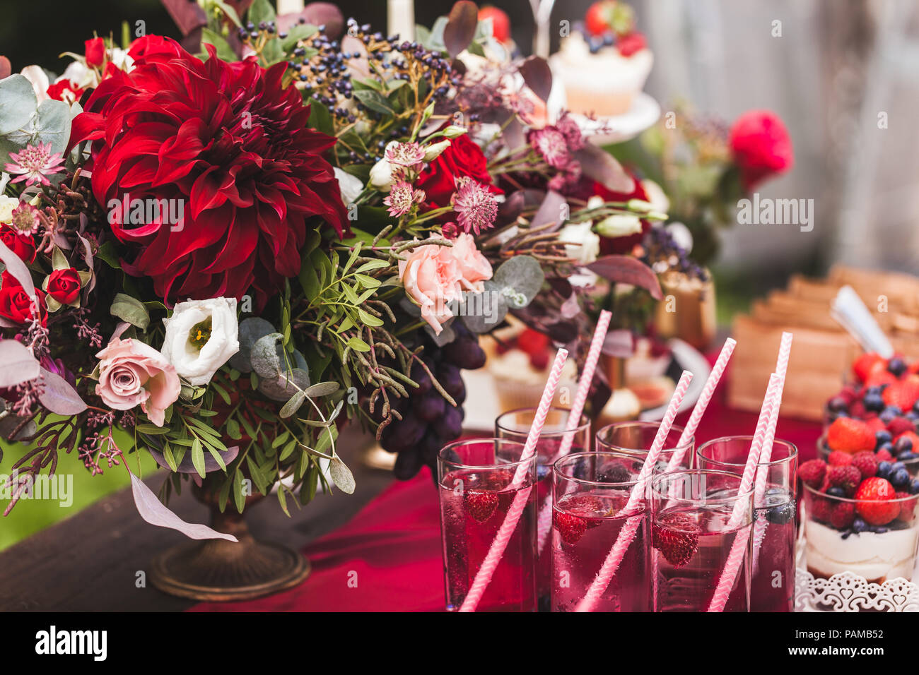 Hochzeit Tisch dekoriert mit roten Blumen, Süßigkeiten, Getränke und Seide. Im rustikalen Stil Stockfoto