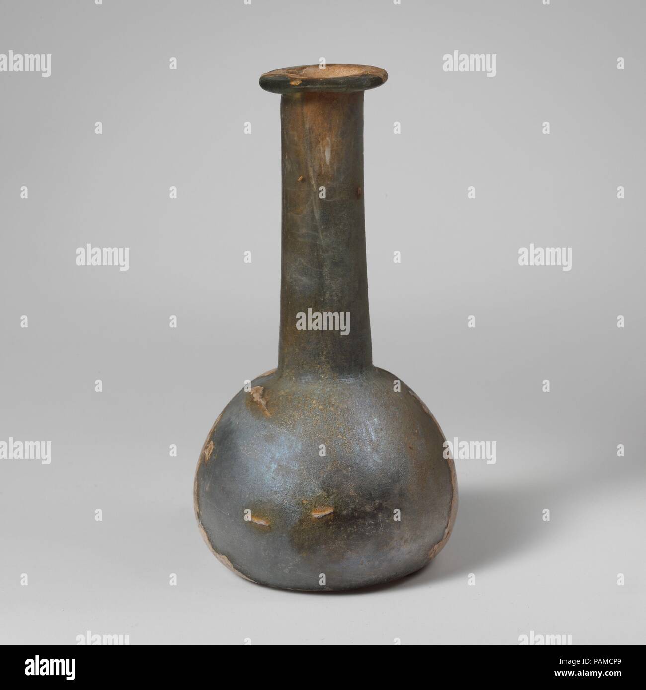 Glas Parfüm Flasche. Kultur: Roman. Abmessungen: 5 1/8 in. (13,1 cm) Andere: 2 11/16 in. (6,9 cm) Durchm. Von rim: 1 1/4 in. (3.2 cm). Datum: Ende 1. bis Mitte 2. Jahrhundert n. Chr.. Translucent Hellblau grün. Rim, gefaltet, über, in, auf und teilweise in den Mund abgeflacht; zylindrische Hals, Erweiterung leicht nach unten, schnittspuren um Base; Hocke, bauchigen Körper; flache Unterseite mit der abgerundeten Kante. Intakt, außer auf Risse in der Seite; pinprick blasen; Mattierung, Lochfraß und Schillern, mit Bereichen der cremige braun Verwitterung. Museum: Metropolitan Museum of Art, New York, USA. Stockfoto