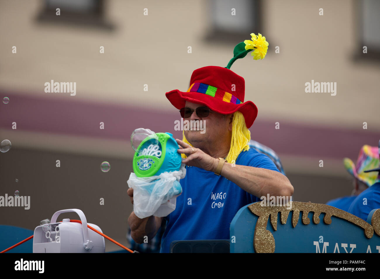Peru, Indiana, USA - Juli 21, 2018 Mann mit dem Hut mit einer Blume, Blasen, die mit einer Maschine im Circus City Festival Parade Stockfoto