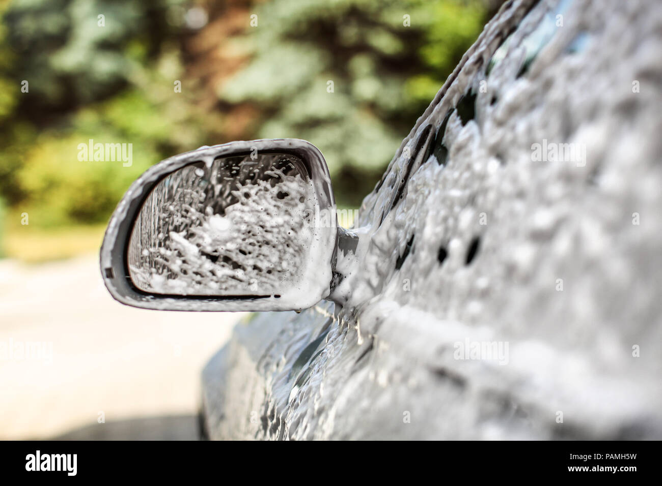 Seite Spiegel der Silver Auto, bedeckt mit Shampoo und Schaum, wenn in der waschstrasse an einem sonnigen Tag gewaschen. Stockfoto