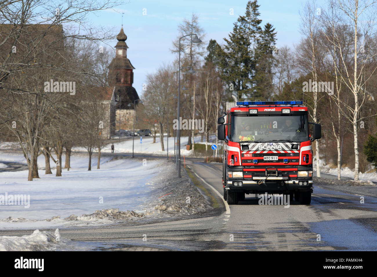 Scania Feuerwehrauto Laufwerke in Pernio Dorfzentrum beim Tag der offenen Tür Veranstaltung, die mittelalterliche Kirche auf dem Hintergrund. Pernio, Salo, Finnland - 18. März 2018. Stockfoto